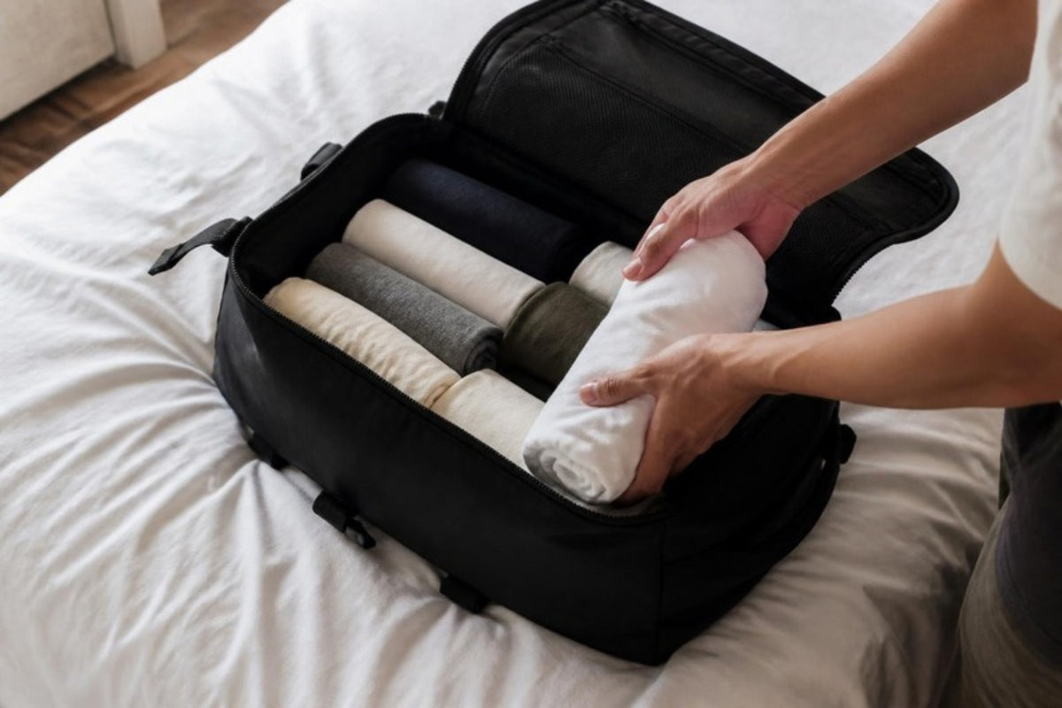 Sac de voyage ouvert sur un lit, rempli de vêtements roulés pour un vol léger