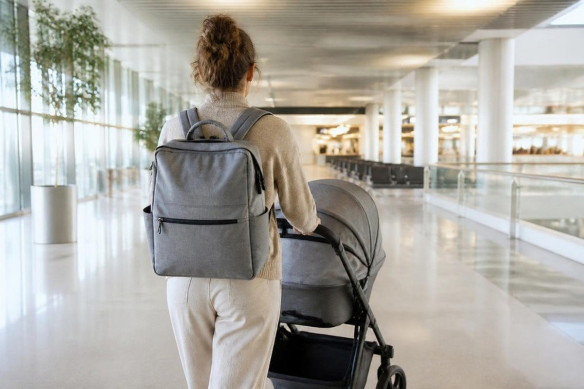 Parent avec un sac à langer sur le dos poussant une poussette dans un aéroport