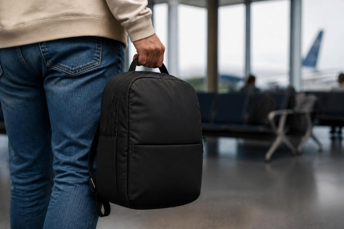 Petit sac à dos tenu à la main en salle d'embarquement, format bagage sous le siège