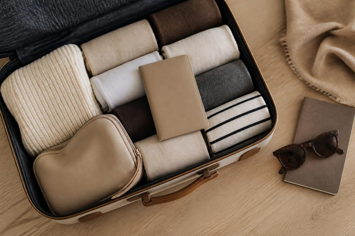 Valise ouverte avec vêtements pliés et accessoires de voyage pour préparer un départ