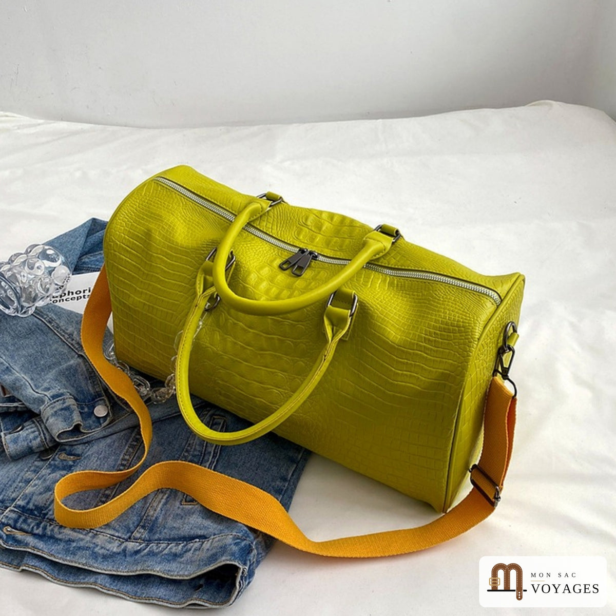 Sac de voyage week-end Croisette jaune posé sur un lit avec sa bandoulière
