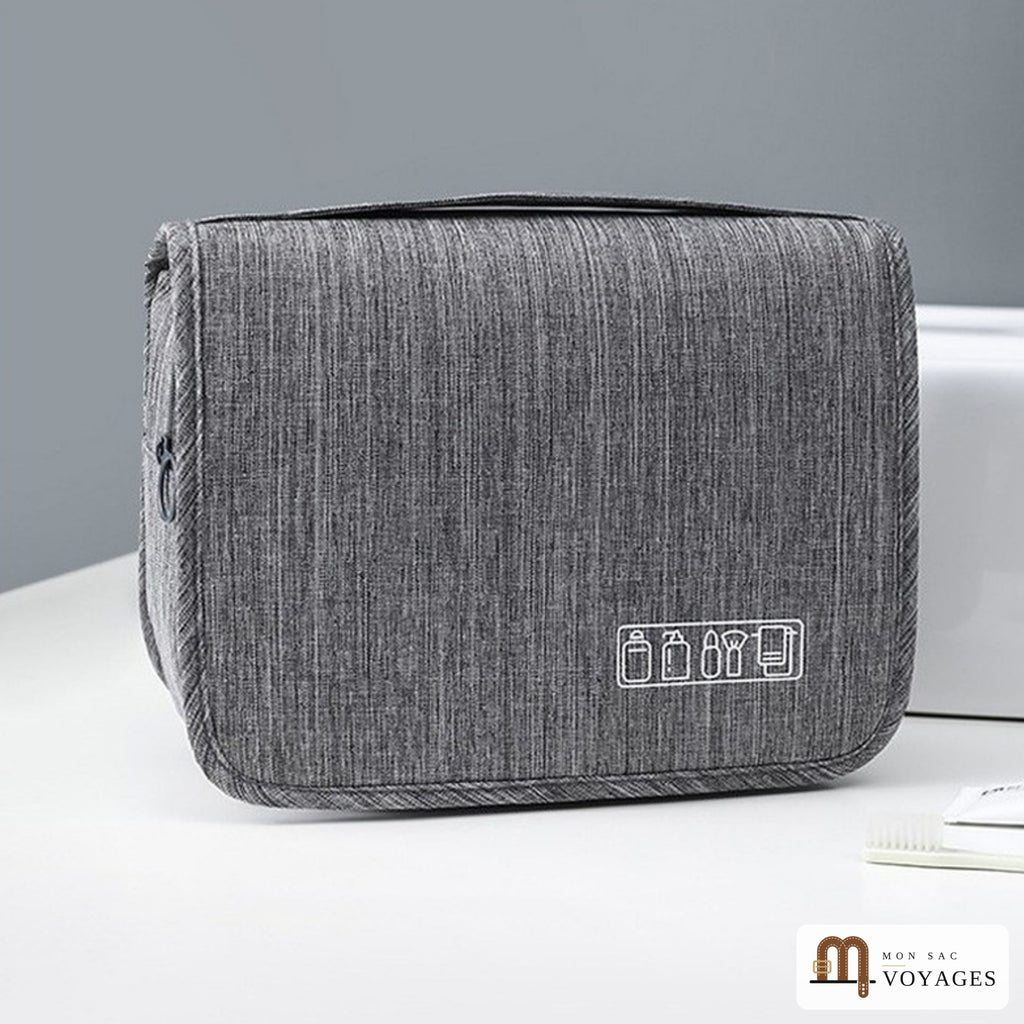 Trousse de toilette Escale grise pliée, posée sur un lavabo, avec sa poignée