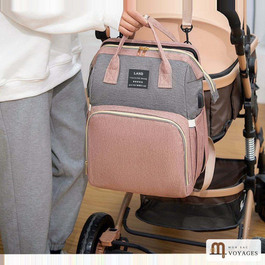 Sac à langer Nid rose et gris porté à la main au-dessus d'une poussette