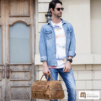 Homme portant un sac de voyage cuir vintage Cognac à la main